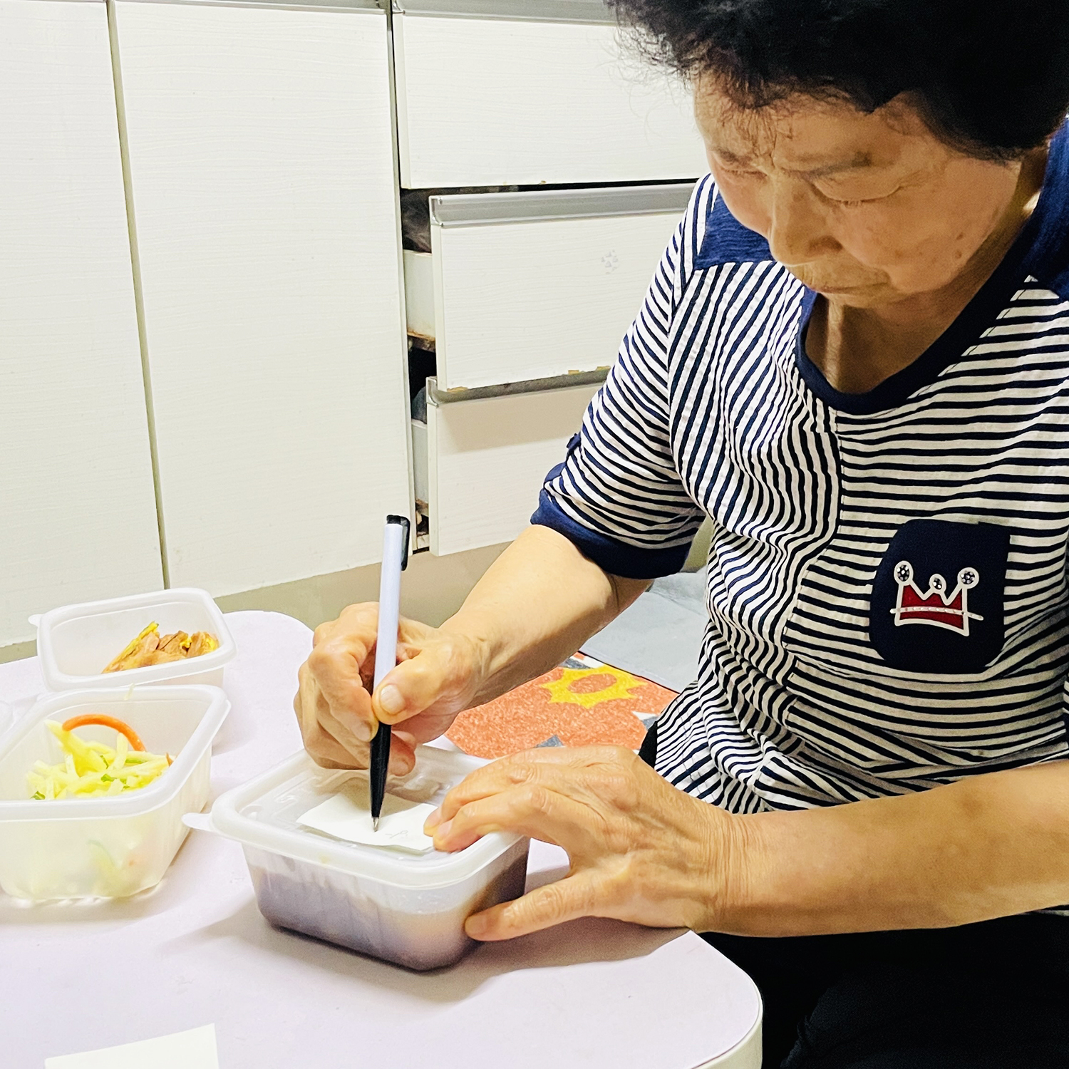 배달된 도시락에 이름표를 붙이는 준우 할머니